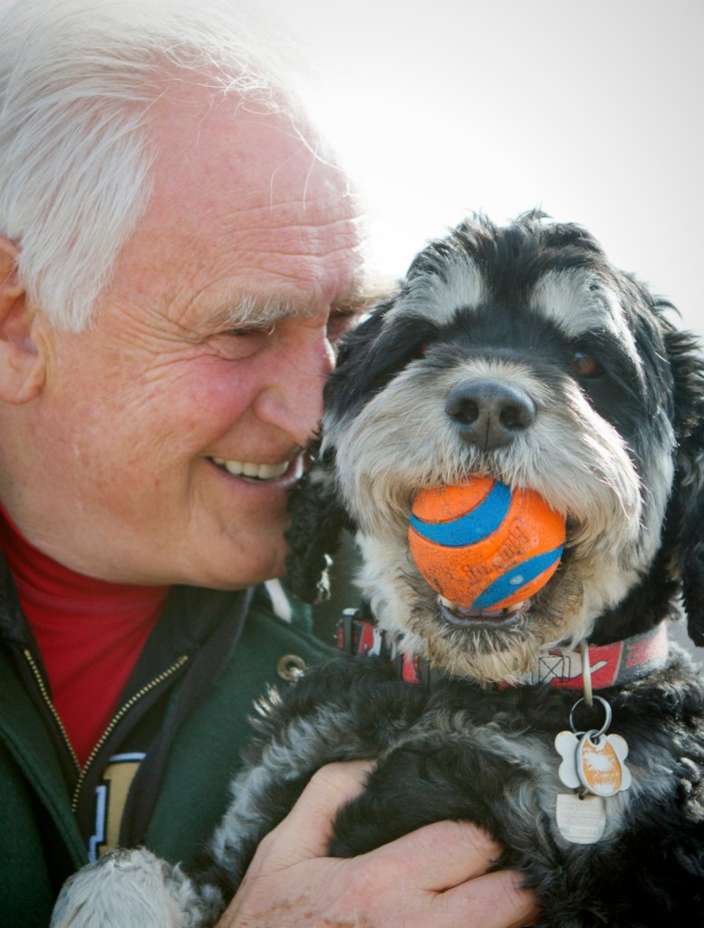 Garry-holding-his-best-friend-Oggie-the-portuguese-water-dog-cross-who-is-holding-is-orange-and-blue-ball